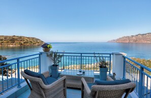 A balcony with wicker furniture, potted plants, and a view of the sea. - Seafront Villa Moments, by Estia (Mochlos)