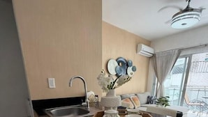 A modern kitchen with a black countertop, a sink, and a ceiling fan. - Modern Ocean View 1BR in La Esperilla, Pool, Gym (Santo Domingo)