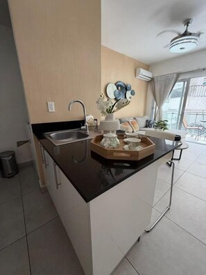 Una cocina moderna con encimera negra, un fregadero y un ventilador de techo.