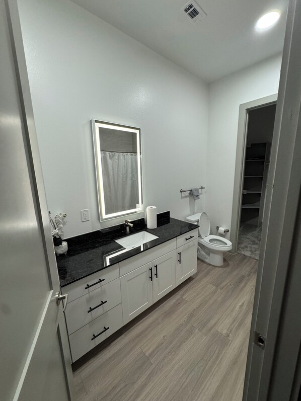 Une salle de bain avec un lavabo blanc, un miroir, des toilettes et un plancher en bois.