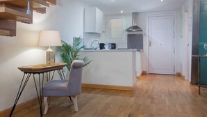 A modern kitchen with white cabinets, a built-in microwave, and a stainless steel range hood. - Exclusive loft in the center of Seville (Sevilla)