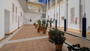 A courtyard with potted plants, a blue glass ceiling, and white walls. - Exclusive loft in the center of Seville (Sevilla)