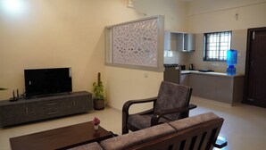 Una sala de estar con televisor, sofá, mesa de centro y una planta en maceta.