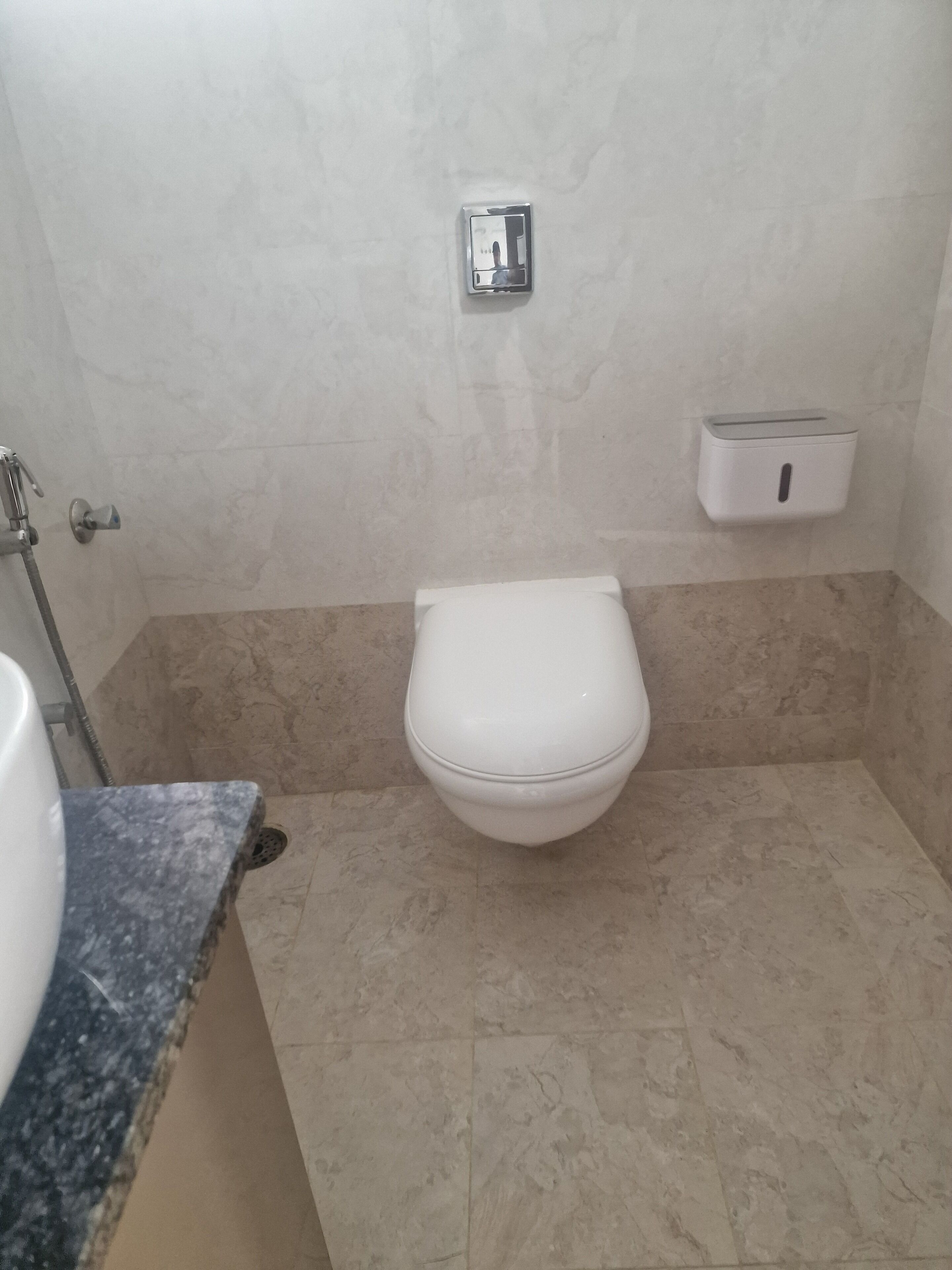 A bathroom with a toilet, a hand dryer, and a paper towel dispenser.