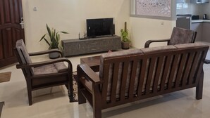 Un salón con sofá, sillas, televisor y un adorno de pared.