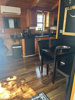 Interior de madera con cocina, comedor y una barra para café.