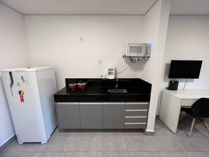 A kitchenette with a refrigerator, stove, microwave, and a small sink. - LK SGutierrez 1 (Belo Horizonte)