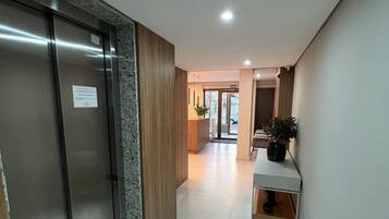A hallway with a reception desk, a plant, and a door with a sign.