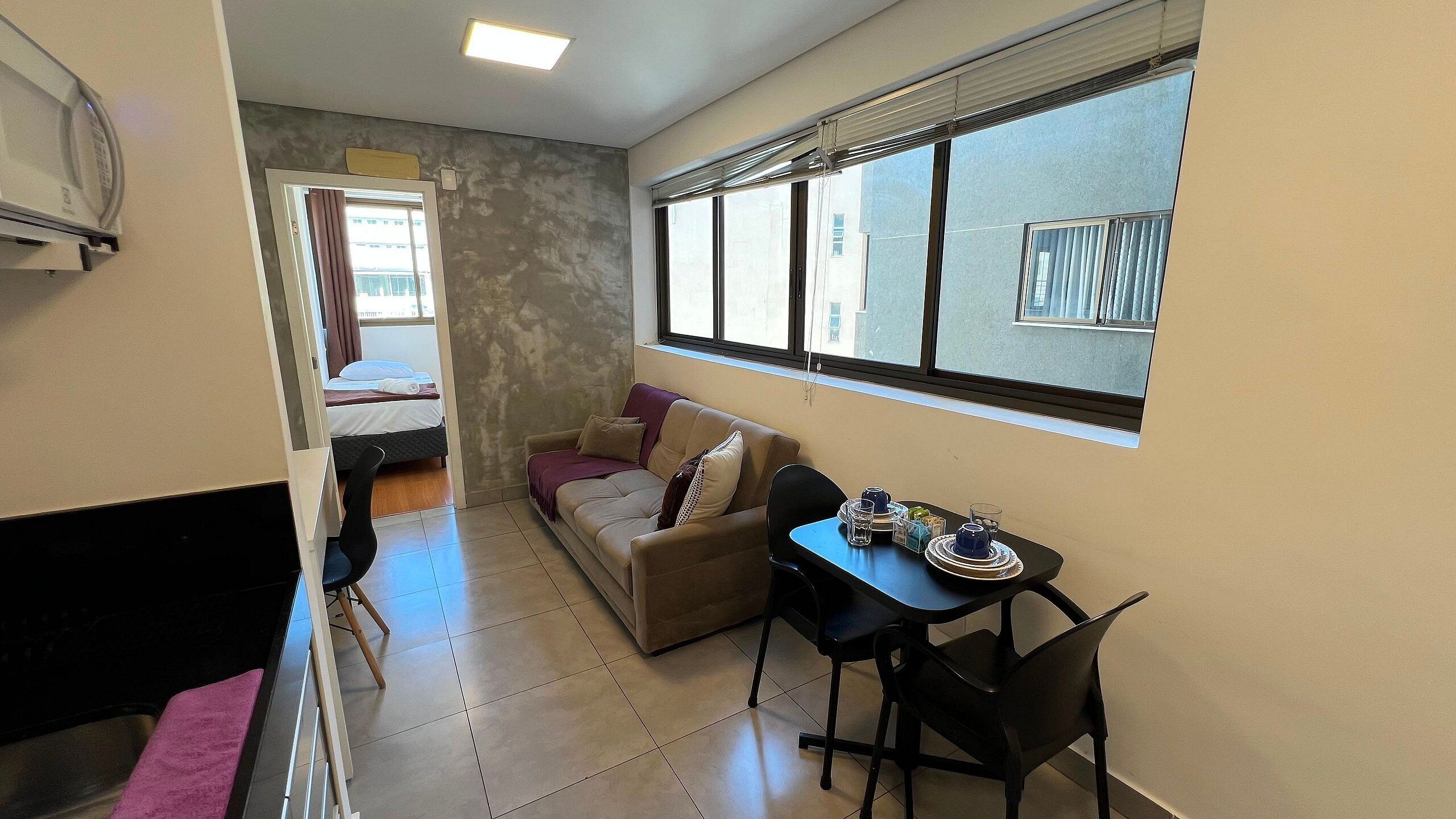 Un espacio habitable compacto con kitchenette, comedor y sofá.