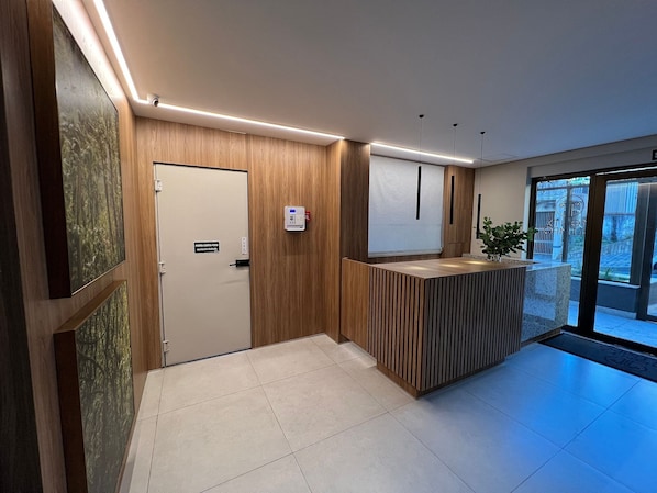 A reception area with a wooden reception desk, a door labeled 'FORSTA COSTA FOGO', and a security intercom.