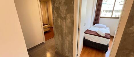 A hotel room with a bed, a bathroom, and a view of the outside.