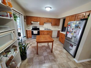 A kitchen with wooden cabinets, a stainless steel refrigerator, a wooden table, and a tiled floor. - Perfect place to enjoy Blacksburg (Blacksburg)