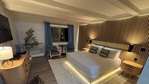 A modern hotel room with a large bed, bedside tables, a desk, a chair, a small table, and a TV. - King Room Near Torch Lake | Hot Tub, Sauna, Resort Amenities (Rapid City)