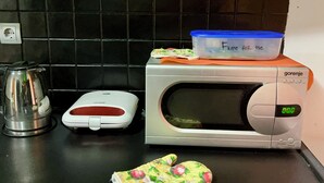 A kitchen with a microwave, a scale, and a kettle on the counter. - Majka Guest House (Kotor)