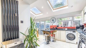A modern kitchen with skylights, a washing machine, and a trash bin. - Stylish 3BR Home | Hot Tub | Near NEC, HS2 & JLR (West Midlands)