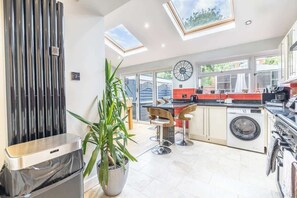 A modern kitchen with skylights, a washing machine, and a trash bin.