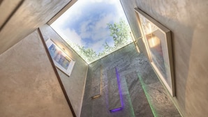 A modern interior with geometric walls, a skylight, and a framed artwork. - Stylish 3BR Home | Hot Tub | Near NEC, HS2 & JLR (West Midlands)