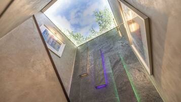 Een modern interieur met geometrische wanden, dakraam en een ingelijste kunstwerk.