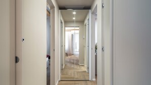 Un pasillo con suelo de espiga, paredes blancas y puertas que dan a habitaciones.