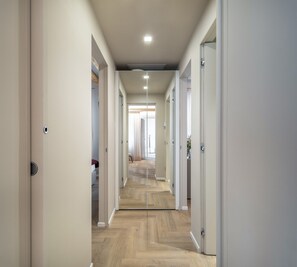 A hallway with a herringbone floor, white walls, and doors leading to rooms. - Sarti Palace - Rose Apartment R&R (Venice)