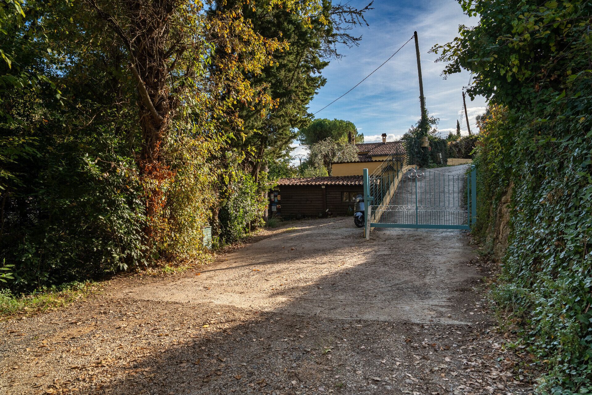 A gravel path leading to a gated entrance with a building in the background.