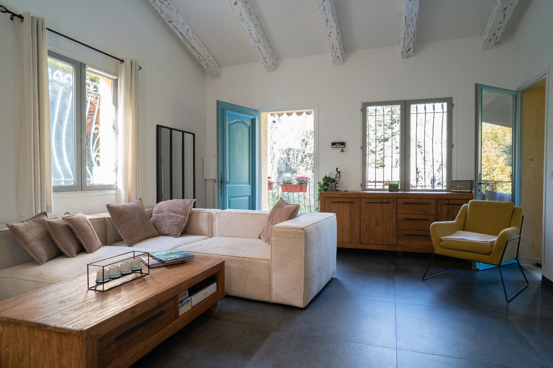 Un salon comprenant un canapé, une table basse, un fauteuil jaune et un meuble en bois.