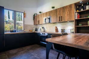 Eine moderne Küche mit Holztischplatte, integriertem Backofen und einem Essbereich mit Tisch und Stühlen.