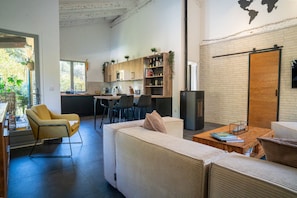 Eine moderne Küche mit weißen Schränken, ein Essbereich mit einer Couch und Stühlen sowie eine große Holztür.