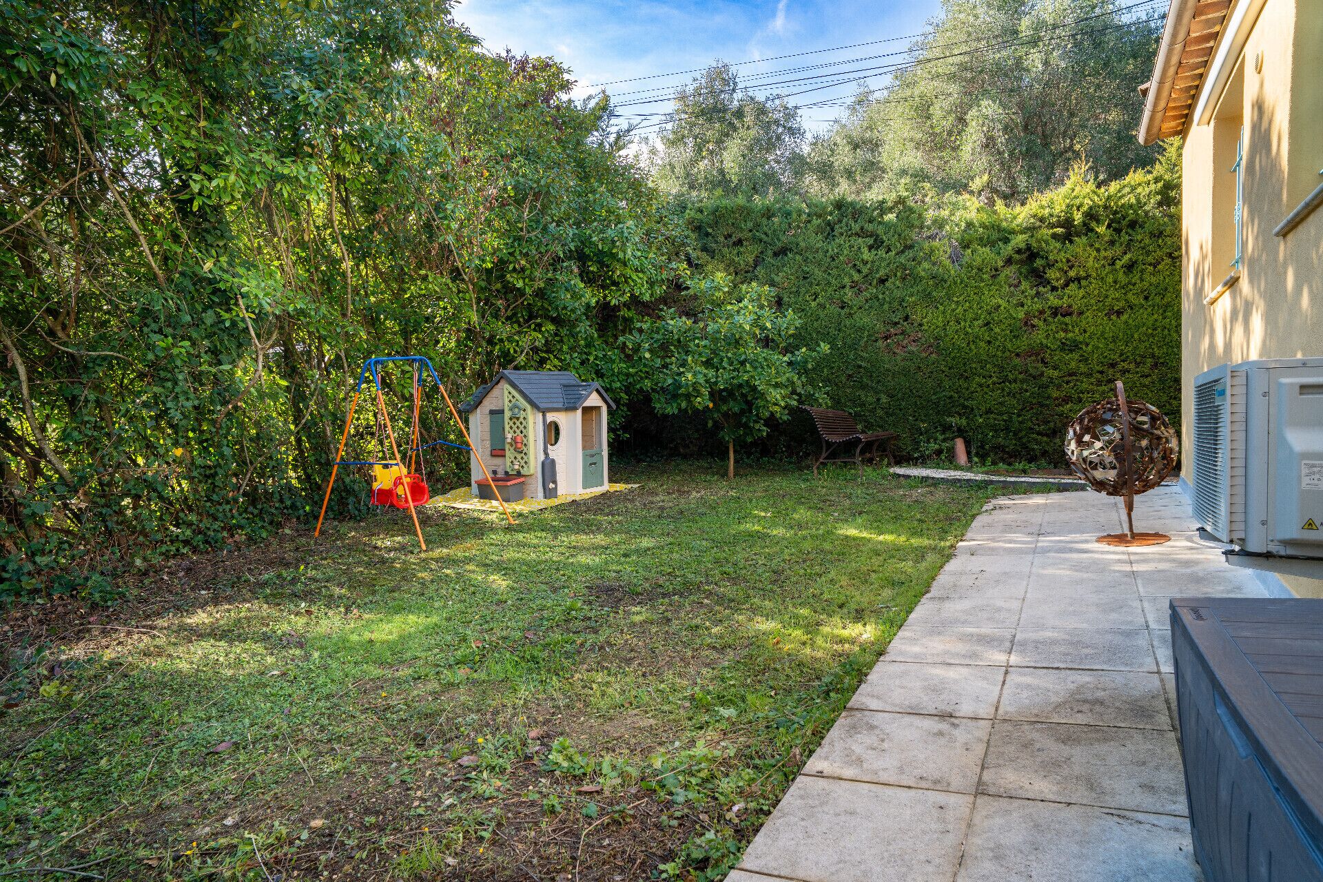 A backyard with a swing set, a small shed, and a garden.