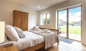 A bedroom with a bed, a wooden wardrobe, a window, and a view of the outside. - Waters Edge 16, Heron Lodge - Lakeside Holiday Home, Hot Tub, Sleeps 8 (Cirencester)