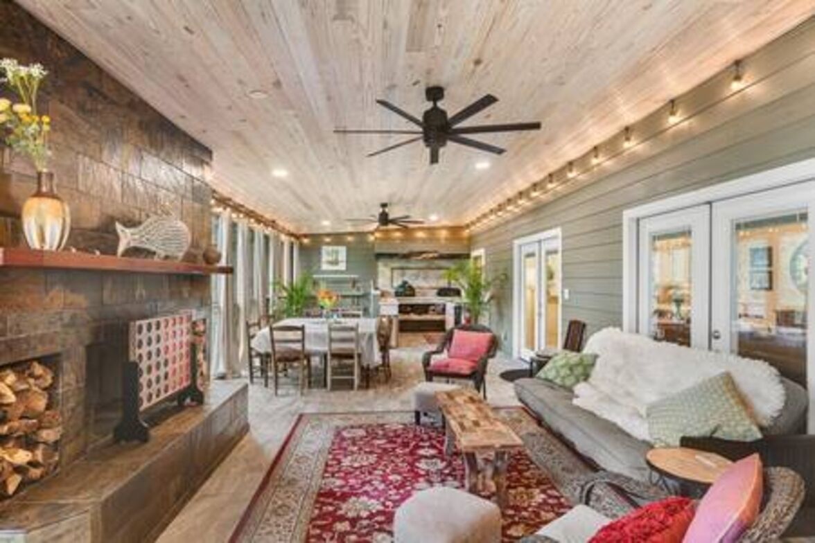 A cozy living room with a fireplace, a ceiling fan, and a dining area.