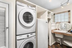 A laundry area with stacked washing machines and a sink. - Downtown and Beach accessible Hot Tub + Firepit (Mobile)