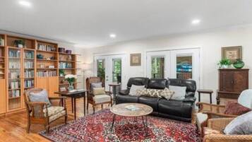 A living room with a black leather sofa, a patterned rug, and a bookshelf filled with books.