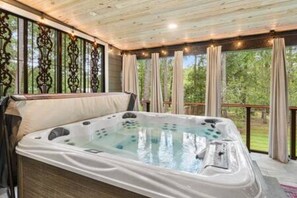 Un jacuzzi en una habitación con techo de madera y ventanas amplias.