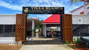The entrance to Villa Blanca with a signboard indicating it offers a restaurant, grills, cocktails, live music, and week-ends.