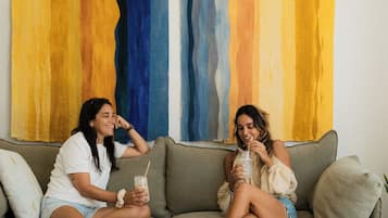 Dos personas sentadas en un sofá con un cuadro abstracto grande al fondo.