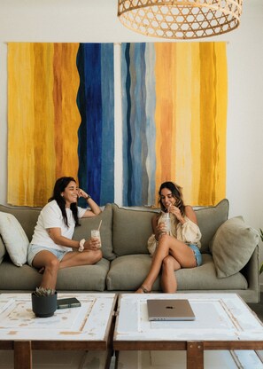 Dos personas sentadas en un sofá con un cuadro abstracto grande al fondo.