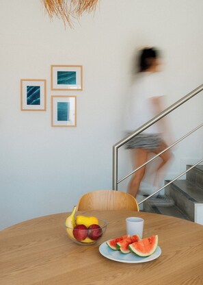 A dining area with a table set for two, featuring a bowl of fruit and a plate of watermelon slices. - Outsite Ericeira Boavista (Mafra)