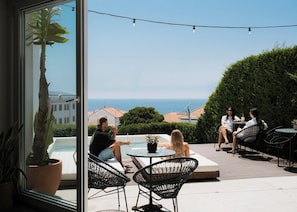An outdoor seating area with a pool, chairs, and tables, overlooking a view of the sea and buildings. - Outsite Ericeira Boavista (Mafra)
