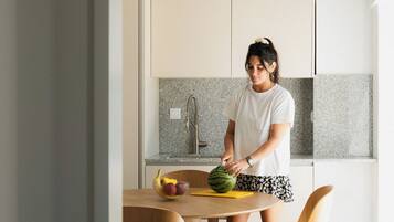 Una cocina moderna con una mujer preparando comida, una mesa de comedor con sillas y una isla de cocina.