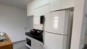 Una cocina moderna con armarios blancos, un refrigerador Bosch, una cubierta de mostrador negra y un horno empotrado.