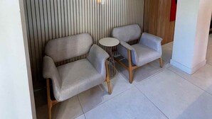 Un interior moderno con dos sofás, una pequeña mesa redonda y un revestimiento de pared con listones verticales.