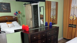 A hotel room with a bed, a dresser, a television, and a mirror.