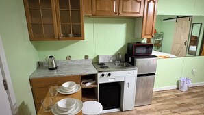 A compact kitchen with wooden cabinets, a microwave, a stove, and a refrigerator.