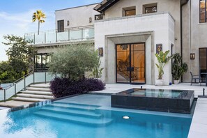 Ein modernes Gebäude mit Pool, einer Treppe zu einem Balkon und Topfpflanzen.