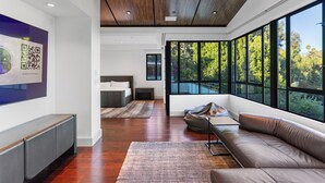 Ein modernes Interieur mit einem großen Fenster, einem Sofa, einem Bett und einem an der Wand hängenden Kunstwerk.