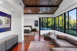 Ein modernes Interieur mit einem großen Fenster, einem Sofa, einem Bett und einem an der Wand hängenden Kunstwerk.