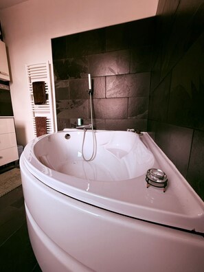 Ein modernes Badezimmer mit einer freistehenden Badewanne, einem Handtuchhalter und einem kleinen Heizkörper am Rand der Wanne.