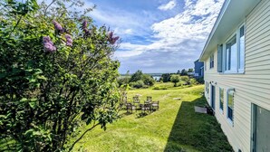 A house with a well-maintained lawn, outdoor seating, and a view of the sky.