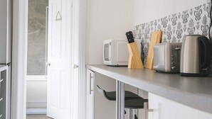 Eine Küche mit einer weißen Mikrowelle, einem Toaster, einem Wasserkocher und einem Holzmesserblock auf der Arbeitsfläche.